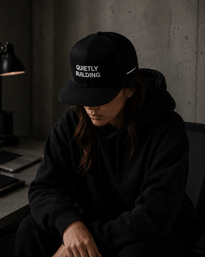 Woman wearing TheCapTribe Quietly Building premium black snapback in modern streetwear environment