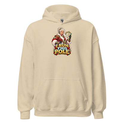 Front view of the Sand Gildan 18500 Christmas hoodie with the I RUN THIS POLE Mrs. Claus artwork printed above the pouch pocket.